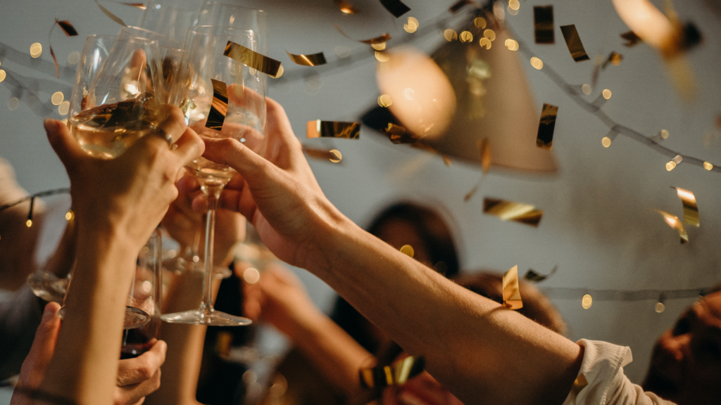 A group raising glasses for a toast during a celebration, with confetti falling.