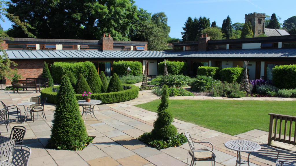 Landscaped pub garden at The Carpenters Arms in Felikirk, featuring paved seating areas with parasols and lush green lawns.