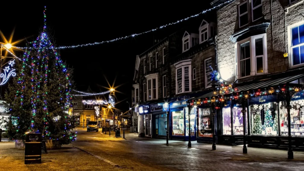 An illuminated Christmas tree and festive string lights on a Harrogate high street at night.